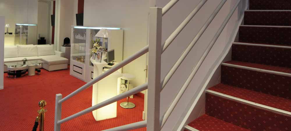 Escaliers et réception d’un établissement élégant avec mobilier moderne et moquette rouge