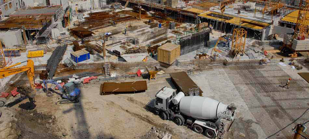 Vue aérienne d'un chantier de construction en cours, avec engins de chantier et camion malaxeur à béton en activité, illustration des travaux d'aménagement urbain de la Coulée Verte à Nice, projet d'espace vert et de promenade urbaine.